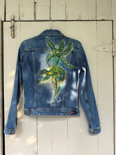 Regular fit handpainted denim jacket with long cuffed sleeves. One of a kind. Designed, painted and signed by the artist. This unique item is handpainted with waterproof textile paint.  Please avoid using the washing machine. Instead, gently hand wash and iron on the reverse side. Artistic Hand Painted Fitted Denim Jacket, Artistic Fitted Hand-painted Denim Jacket, Artistic Hand Painted Blue Denim Jacket, Hand-painted Fitted Cotton Denim Jacket, Hand Painted Fitted Cotton Denim Jacket, Artistic Long Sleeve Cotton Denim Jacket, Hand Painted Blue Denim Jacket With Long Sleeves, Artistic Hand Painted Denim Jacket For Fall, Hand Painted Blue Long Sleeve Denim Jacket