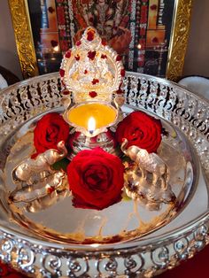 a silver tray with red roses on it and a lit candle in the center surrounded by candlesticks