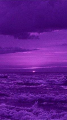 the sky is purple and there are waves in the water below it, as well as dark clouds