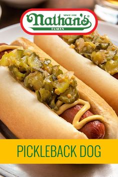 two hotdogs with pickles and mustard on them are sitting on a plate