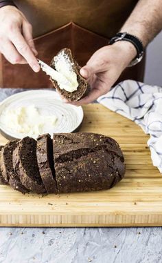 a person is spreading cream on top of some bread and it's cut in half