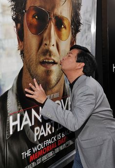 a man kissing another man's face in front of a poster for the hangover