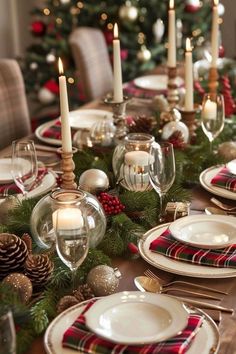 a christmas table setting with candles, plates and plaid napkins on the placemat