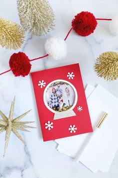 a christmas card with an image of two people on it and some pom poms