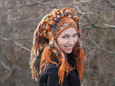 a woman wearing a knitted hat and scarf in front of some bare tree branches