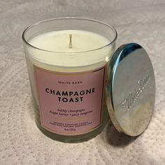 a white candle sitting on top of a bed next to a metal container with a pink label