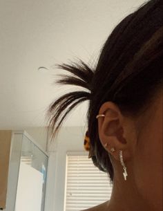 a woman with ear piercings looking at herself in the mirror