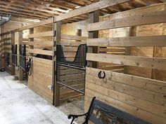 several horses are lined up in their stalls at the stable, with wooden walls and flooring