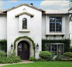 a large white house with lots of windows and greenery on the front lawn,