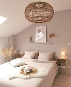 a white bed sitting under a light fixture in a bedroom