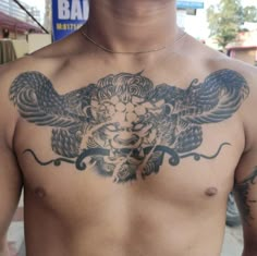 a man with an eagle tattoo on his chest is standing in front of a building