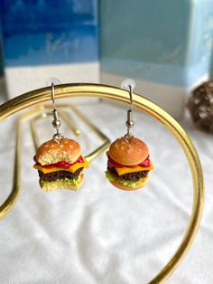 two hamburgers are hanging from gold hoop earrings