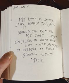 a hand holding an open book with writing on it