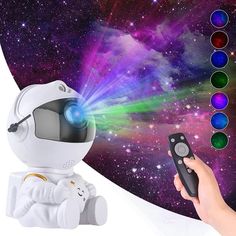 a hand holding a remote control next to an image of a spaceman in the background