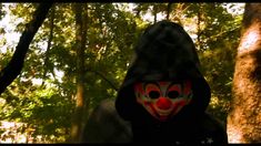 a person wearing a clown mask in the woods