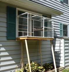 a white bird cage sitting on top of a wooden stand in front of a house