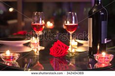 a table topped with two wine glasses and a red rose next to a bottle of wine