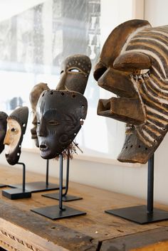 several african masks are on display in a room with wooden flooring and white walls