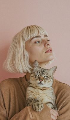 a woman with blonde hair holding a cat