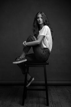 black and white photograph of a woman sitting on a chair with her legs crossed in the air