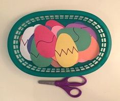 a green basket filled with cut out easter eggs next to purple scissor scissors