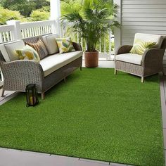 an outdoor living room with green grass and wicker furniture on the porch area rug