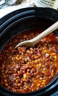 a wooden spoon in a slow cooker filled with beans