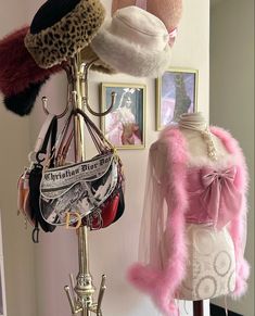 several hats and purses are hanging on a rack in front of a dress mannequin