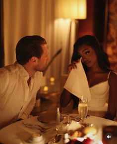 a man and woman sitting at a table in front of each other with napkins