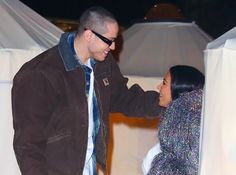 a man and woman standing next to each other in front of white tents at night