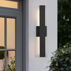 a wall light mounted on the side of a building next to a potted plant