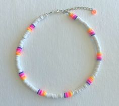 a bracelet with multicolored beads and a silver chain on a white surface,