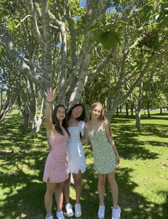 two girls standing under a tree waving at the camera