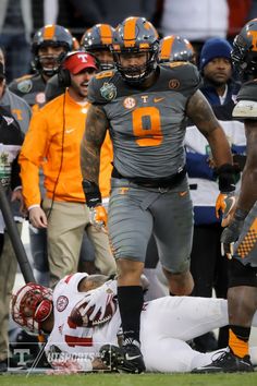 a football player is laying on the ground with his head in his hands and other players behind him