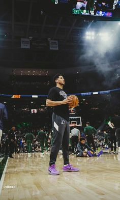 a man standing on top of a basketball court with a ball in his hand and people watching from the sidelines