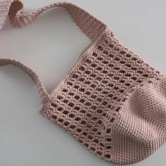 a crocheted bag with a bow on the handle is laying on a table