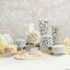 there are many different candies on display in the table with white and yellow flowers