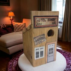 a small wooden house sitting on top of a white round table in a living room