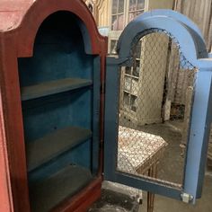 an old blue cabinet with a mirror on it's front and side doors open