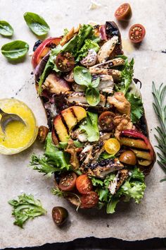 grilled chicken and vegetable salad with lemon dressing on a marble surface next to fresh herbs