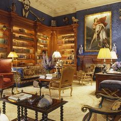 a living room filled with lots of furniture and bookshelves covered in paintings on the walls