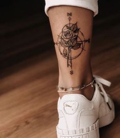 a woman's foot with a rose tattoo on it and a compass in the background