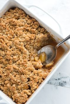 a casserole dish filled with apple crumbles and a spoon in it