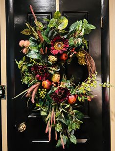 a black door with a wreath on it and flowers hanging off the side of it