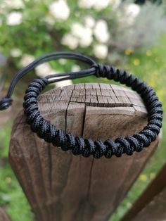 a black rope bracelet sitting on top of a wooden post