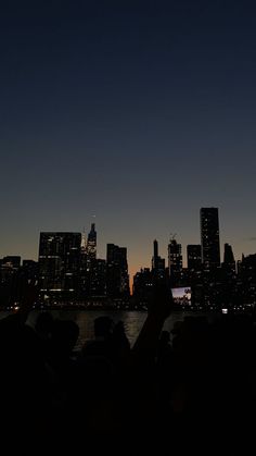 people are taking pictures with their cell phones in front of the city skyline at night