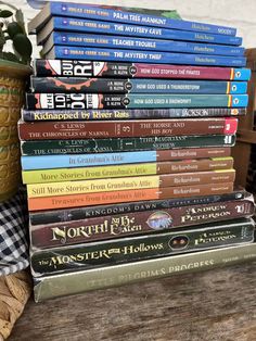 a stack of books sitting on top of a wooden table next to a potted plant