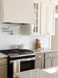 a stove top oven sitting inside of a kitchen next to white cupboards and counter tops