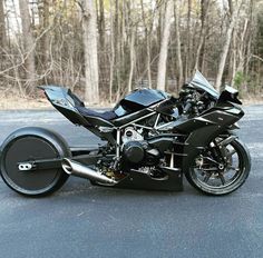 a black motorcycle is parked on the side of the road in front of some trees