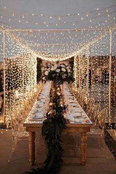 a long table with lights and greenery on it